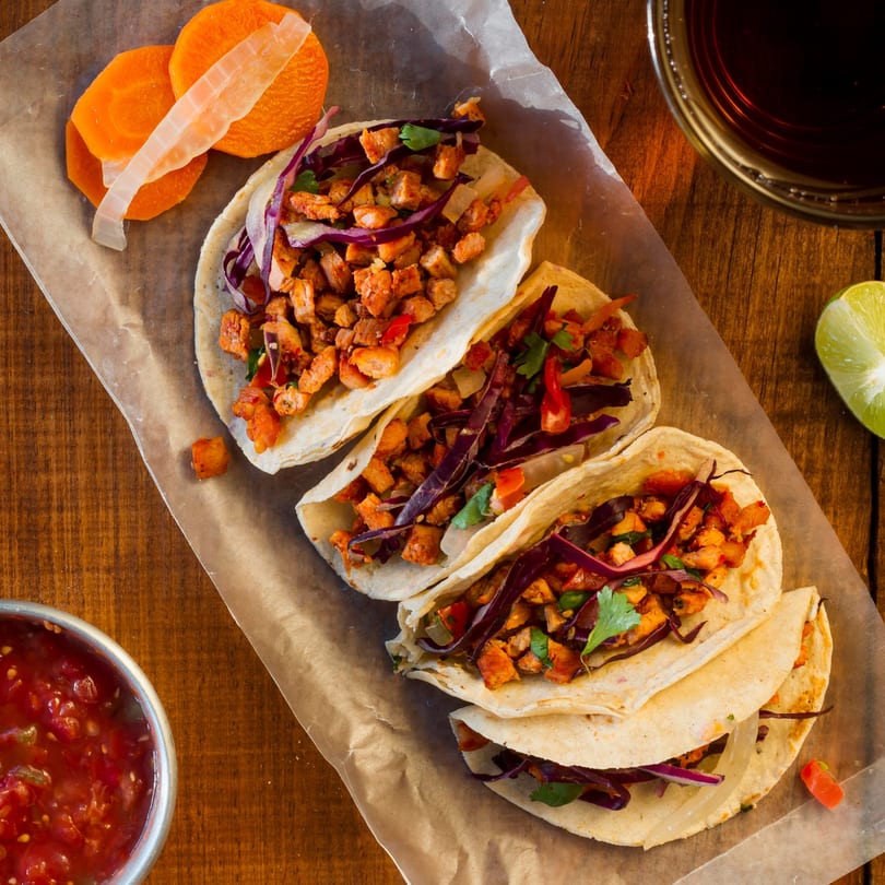Four Rose's Mexican Restaurant tacos with meat, red cabbage, and cilantro, served with salsa and lime.