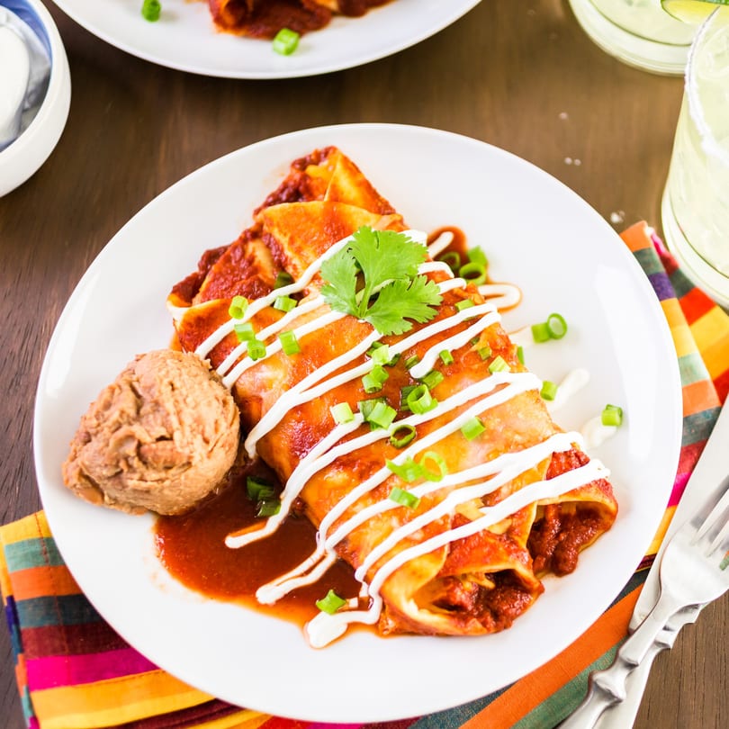 Rose's Mexican Restaurant enchiladas with red sauce, sour cream, cilantro, and refried beans.
